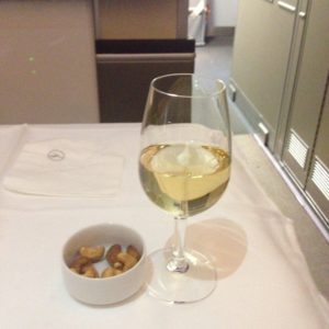 a glass of wine and a bowl of nuts