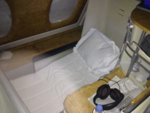a bed with a white sheet and headphones on a table