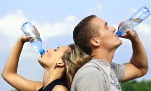 a man and woman drinking water from bottles