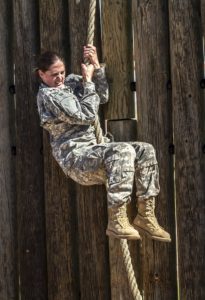 a woman in military uniform climbing a rope