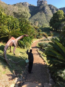 a man standing on a path near a dinosaur statue