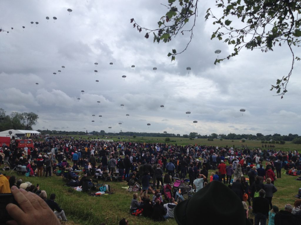 a large group of people in a field with parachutes in the sky